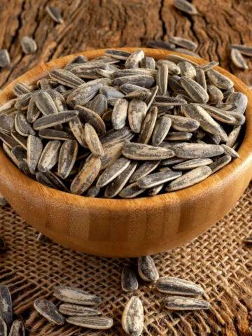 A wooden bowl holding roasted sunflower seeds