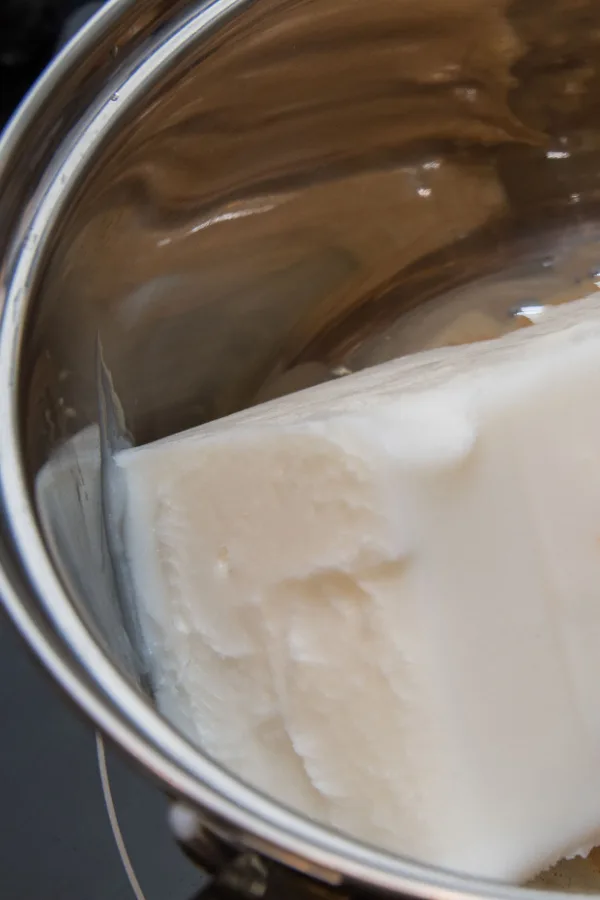 A block of tallow in a saucepan starting to melt